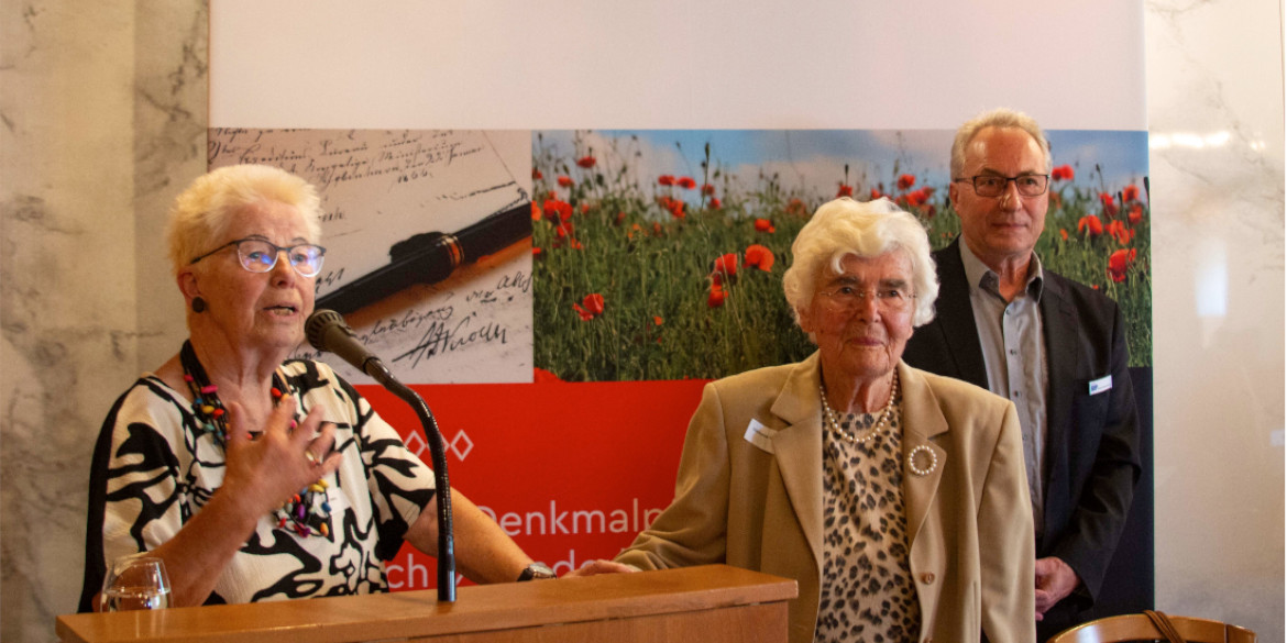 3 Personen vor Stellwand