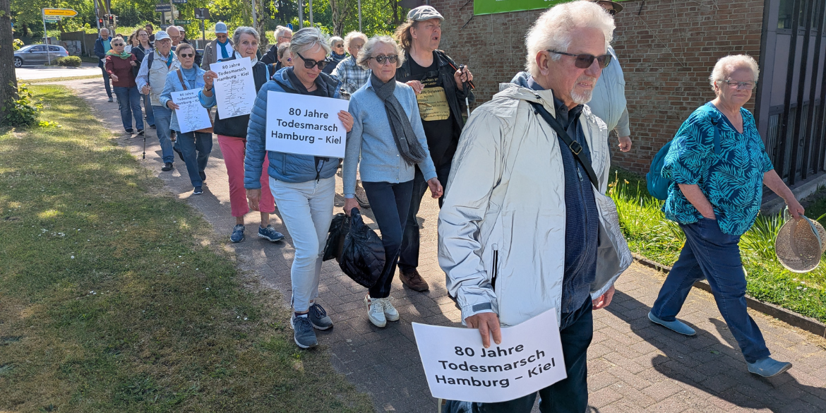 Menschen bei Gedenkwanderung mit Schildern 