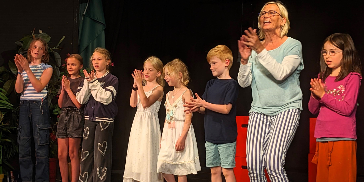 Klatschende Kinder und eine Frau auf Theaterbühne