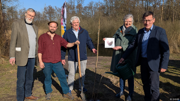 Personengruppe um jungen Baum