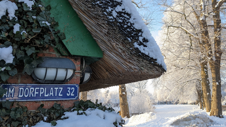 Hausecke, dahinter Dorfplatz im Tiefschnee