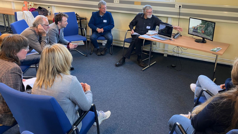 Workshop-Teilnehmende sitzen im Kreis um einen Bildschirm