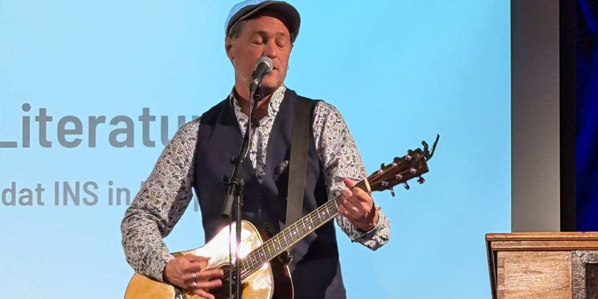 Sänger Gerrit Hoss mit Gitarre auf der Bühne