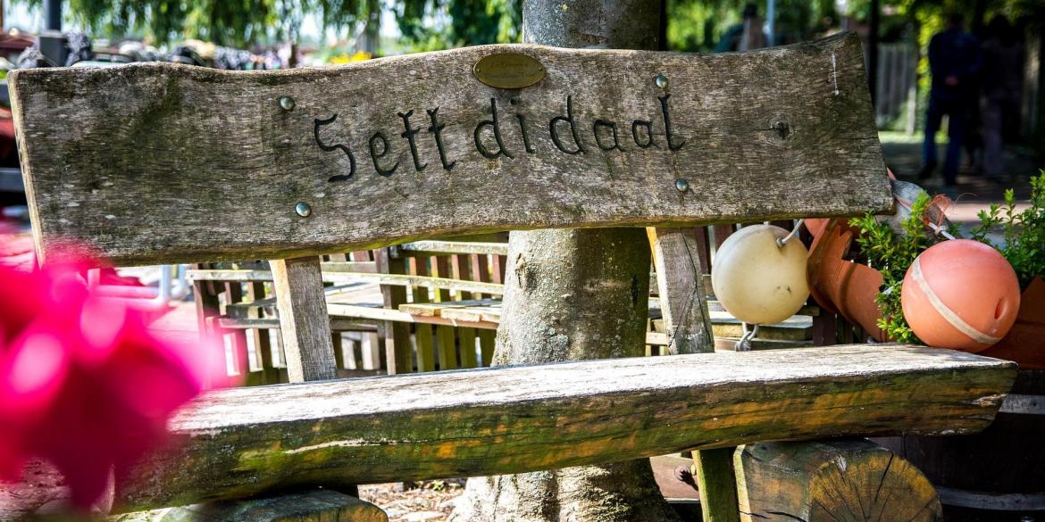Holzbank mit Aufschrift "Sett di daal"