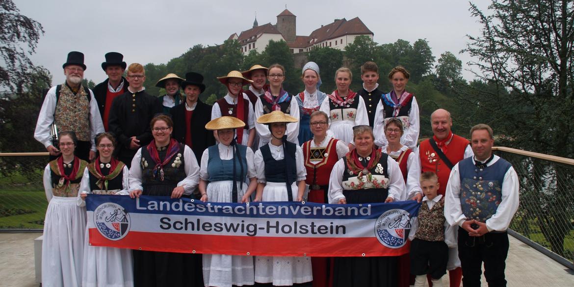 Menschengruppe in Tracht mit Banner: "Landestrachtenverband Schleswig-Holstein"