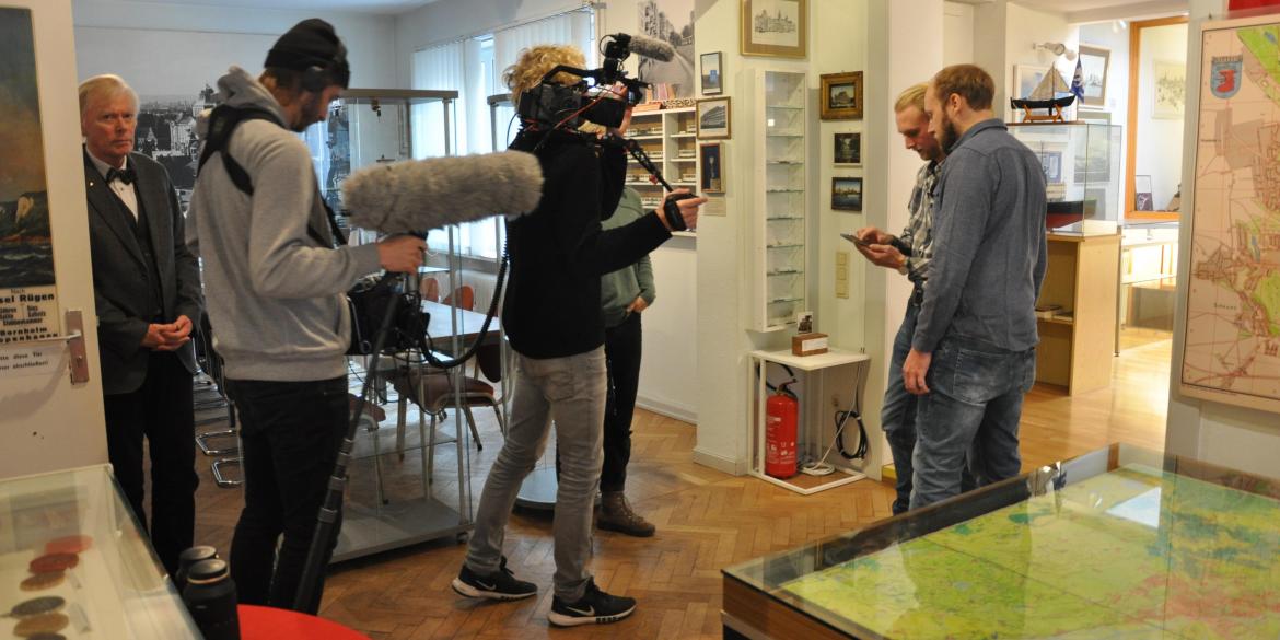 Sieben Personen bei Filmaufnahmen in einem Museum