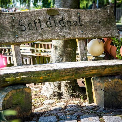 Holzbank mit Aufschrift "Sett di daal"