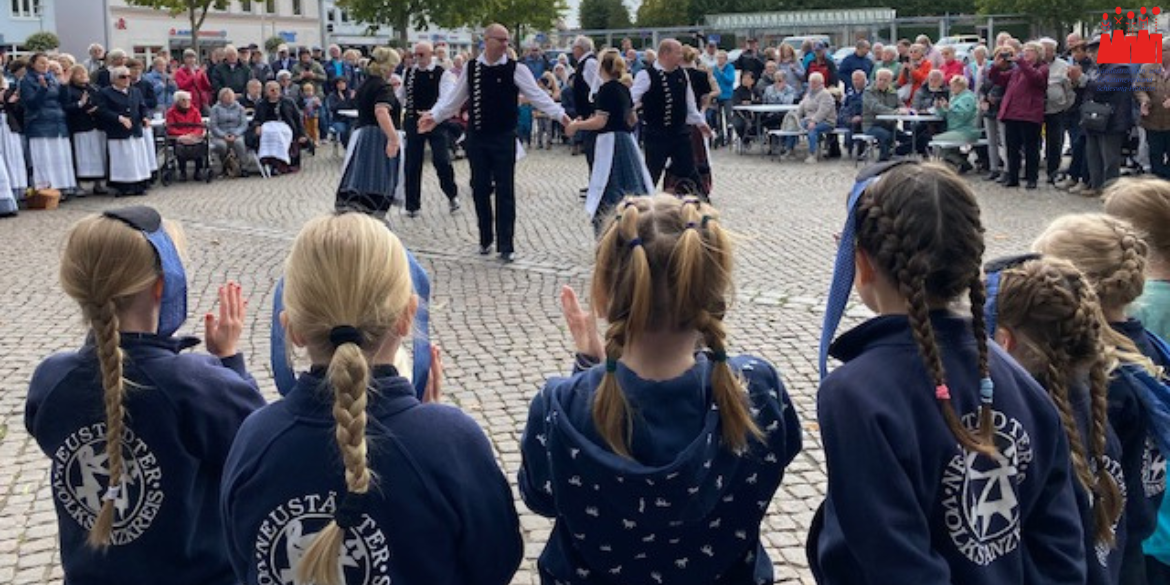 Tänzer*innen in Tracht auf Marktplatz umringt von Publikum