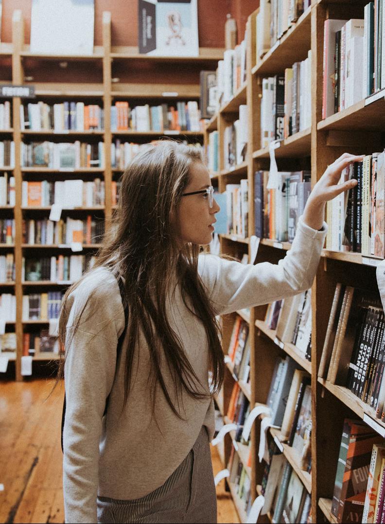 Frau greift in Bibliothek in ein Bücherregal
